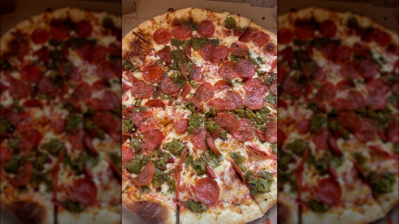 A large pizza pie with lots of pepperoni and hatch green chiles