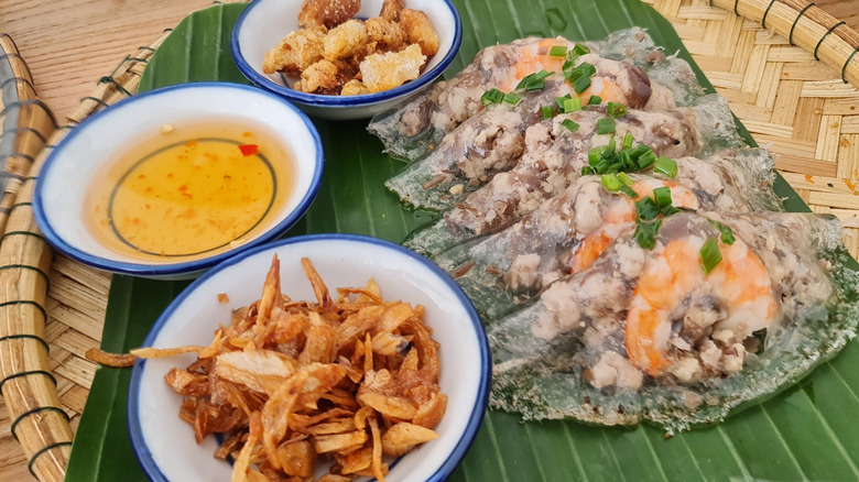 wicker tray of Bánh bột lọc on banana leaf with dipping sauces and other fillings
