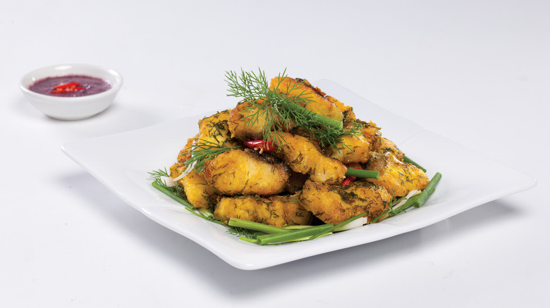 white plate of Chả Cá Lã Vọng with dipping sauce on white background