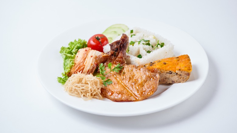 Vietnamese Broken Rice is served with grilled pork on white plate with white background