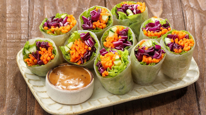 Vietnamese spring rolls with dipping sauce on a dish on a wooden table