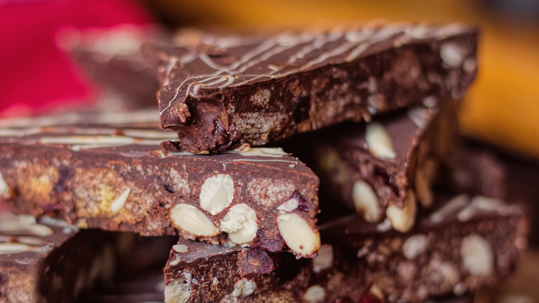 A close up of slices of chocolate tiffin with nuts stacked on top of each other