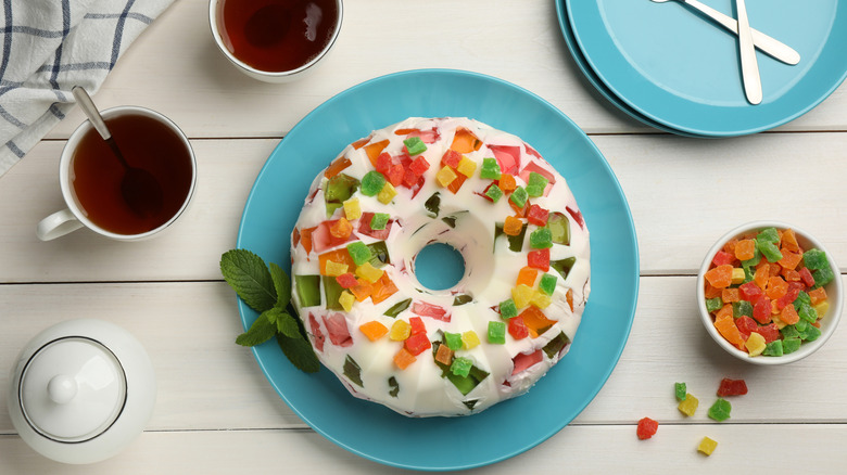A round cake made with whipped cream and colorful Jell-O chunks on a blue plate