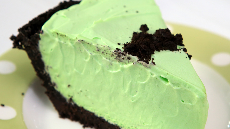 A close-up of a creamy mint-green pie with a chocolate cookie crust