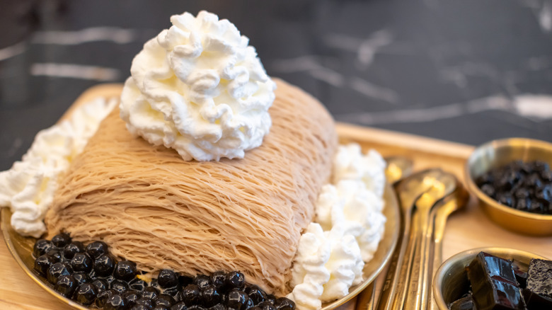 A plate of Korean bingsu topped with whipped cream and served with tapioca pearls