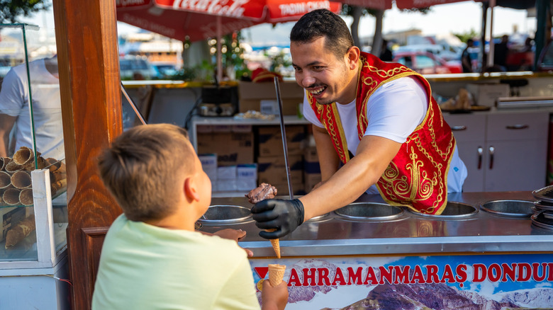 A Turkish dondurma street vendor serving ice cream to a child