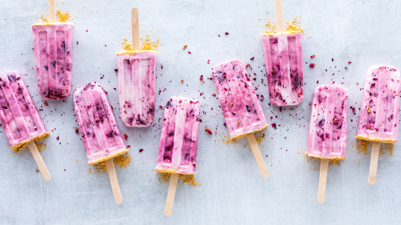 Nine homemade popsicles scattered with rose petals