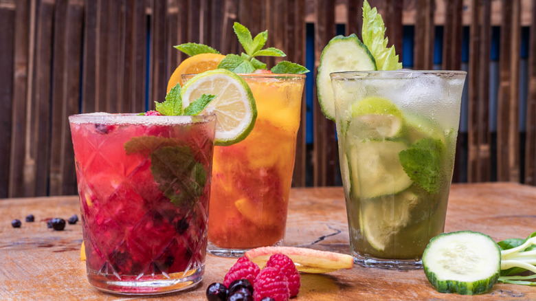 Three beverages in glasses filled with various fruits