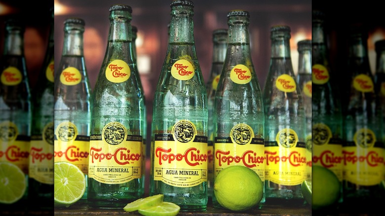 Glass bottles of Topo Chico with fresh lime slices on counter
