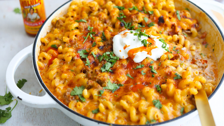 Taco pasta in casserole pot, topped with sour cream and fresh cilantro