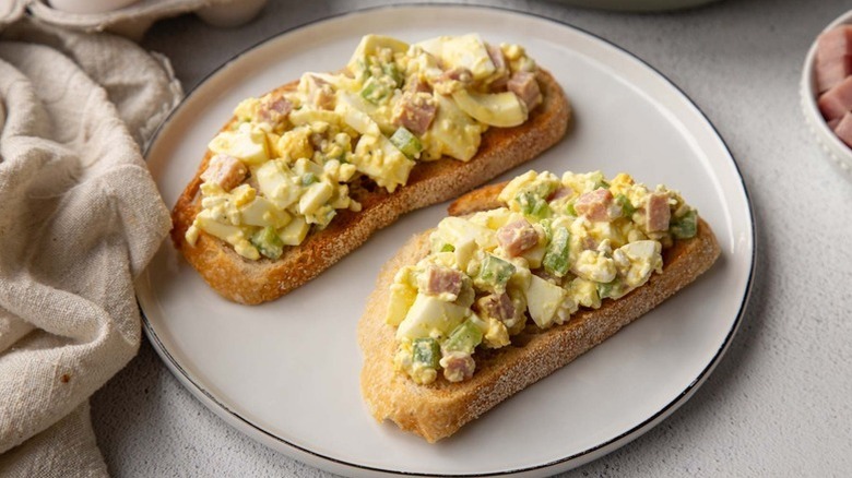 Two slices of toast topped with ham and egg salad