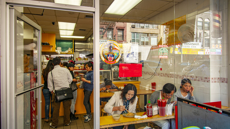 people eating in a small hole-in-the-wall restaurant in New York City