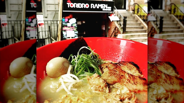 a bowl of ramen in front of Toribro Ramen restaurant in nyc