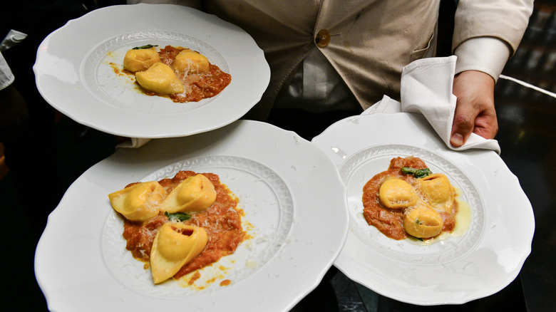 server carrying plates of tortellini at Torrisi NYC