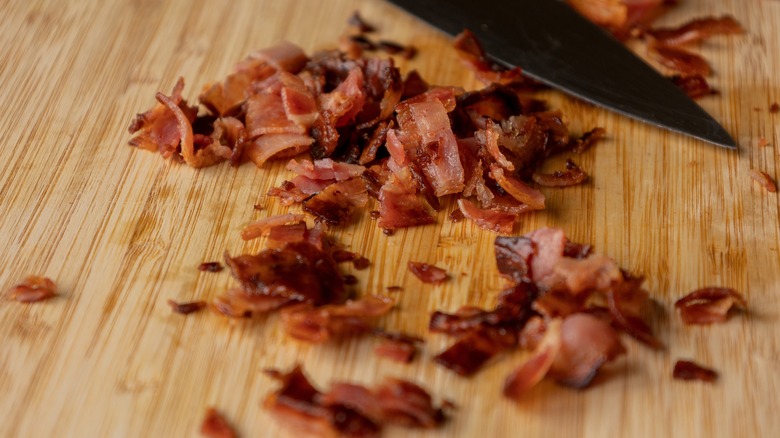 Chopped cooked bacon on wooden cutting board