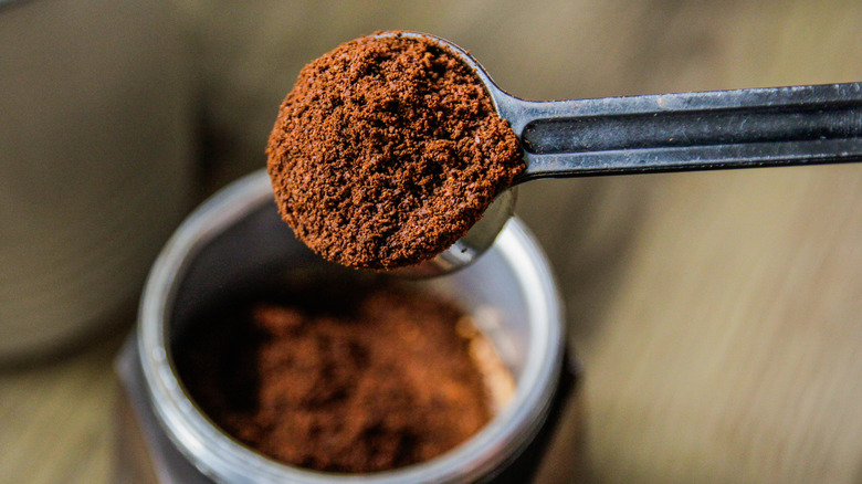 Scooping ground coffee from jar