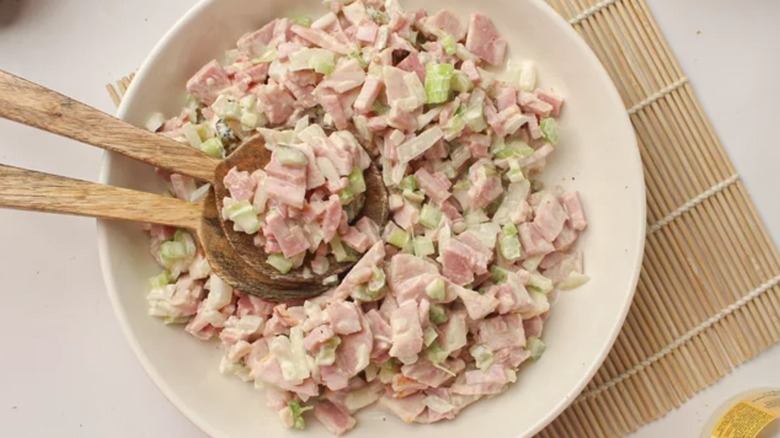 Creamy ham salad in bowl with wooden spoons