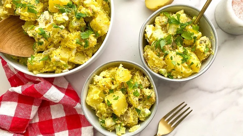 Individual bowls of potato salad topped with herbs