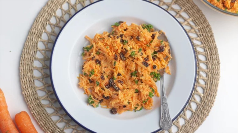 Carrot raisin salad in a bowl sprinkled with parsley