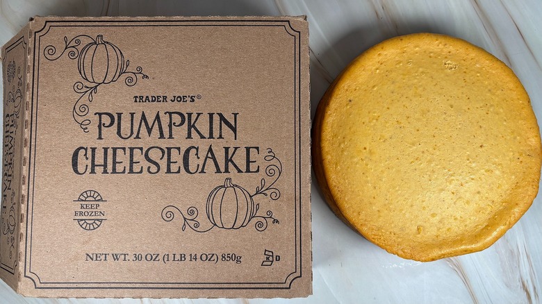 Trader Joe's Pumpkin Cheesecake next to packaging on marbled surface