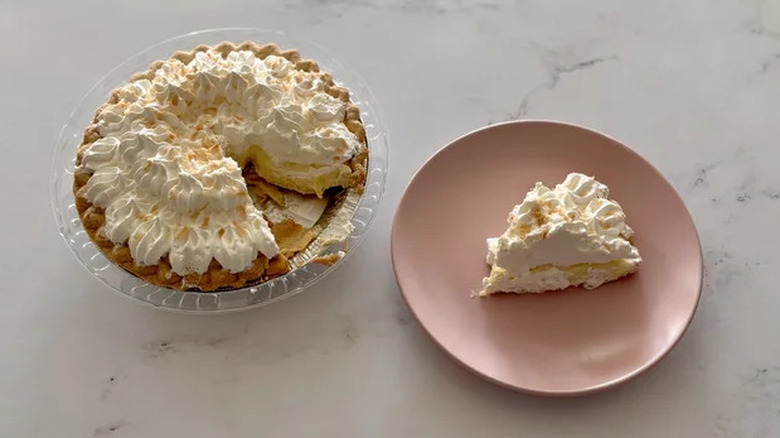 Bakery Coconut cream pie slice on plate with a whole pie on the side