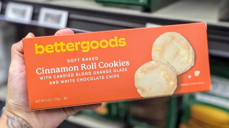 A person holding a box of bettergoods soft-baked cinnamon roll cookies