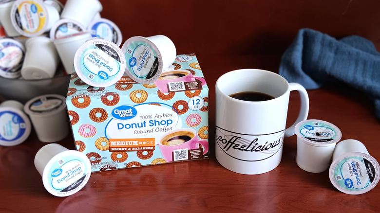 Great Value Donut Shop coffee pod box, surrounded by loose pods and a mug of black coffee