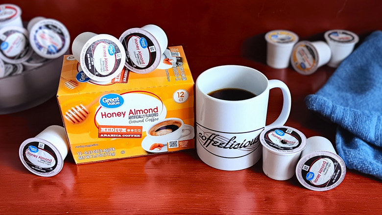 Great Value Honey Almond coffee pod box, surrounded by loose pods and a mug of black coffee