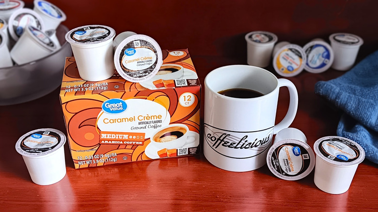 Great Value Caramel Crème coffee pod box, surrounded by loose pods and a mug of black coffee