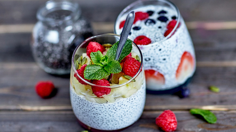 Two glasses of chia pudding topped with fresh mint and berries