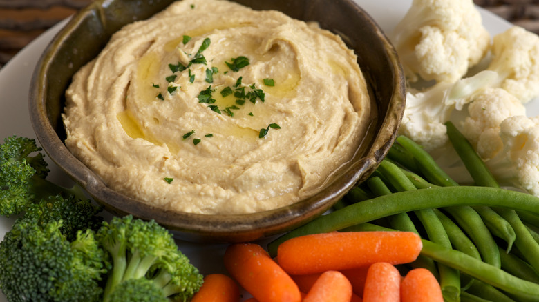 Bowl of hummus surrounded by fresh vegetables
