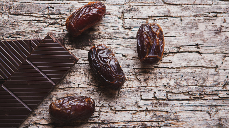Four dates beside pieces of dark chocolate