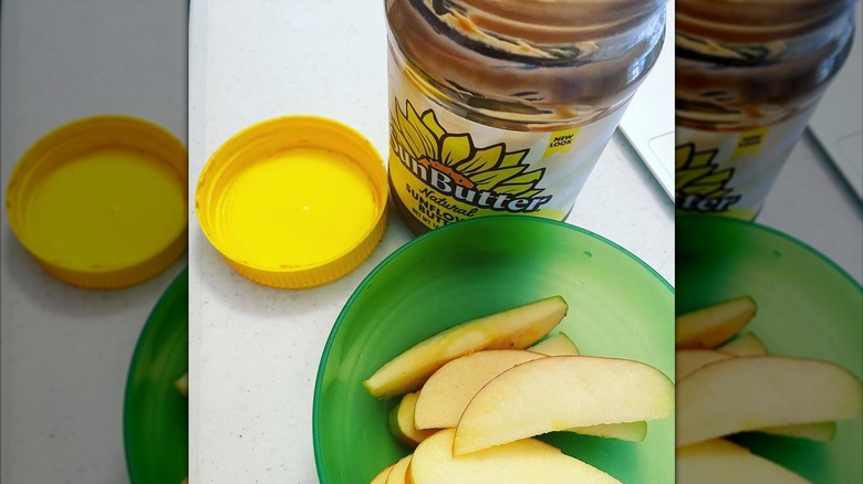 Bowl of sliced apples with jar of SunButter