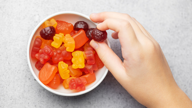 Girl's hand taking fruit gummies from bowl