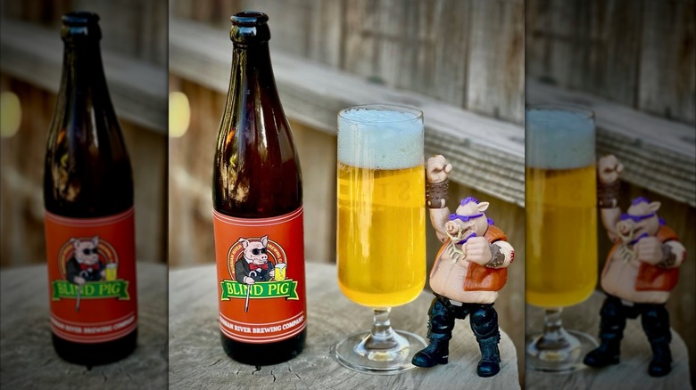 A bottle of Blind Pig next to a full glass and pig action figure