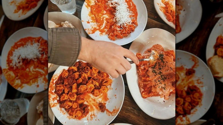 a hand reaching for a forkful of pasta dish