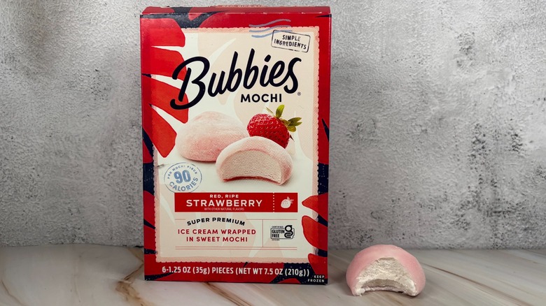 Bubbies Red, Ripe Strawberry mochi box next to mochi with bite taken out of it on table