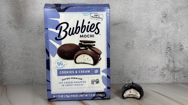Bubbies Cookies & Cream mochi box next to mochi with bite taken out of it on table