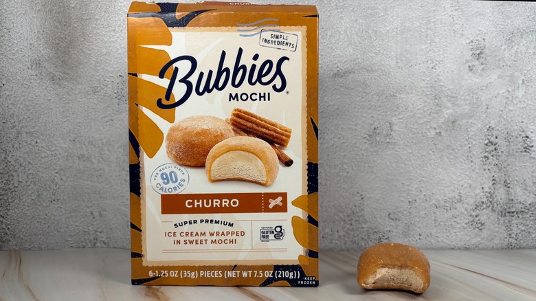 Bubbies Churro mochi box next to mochi with bite taken out of it on table