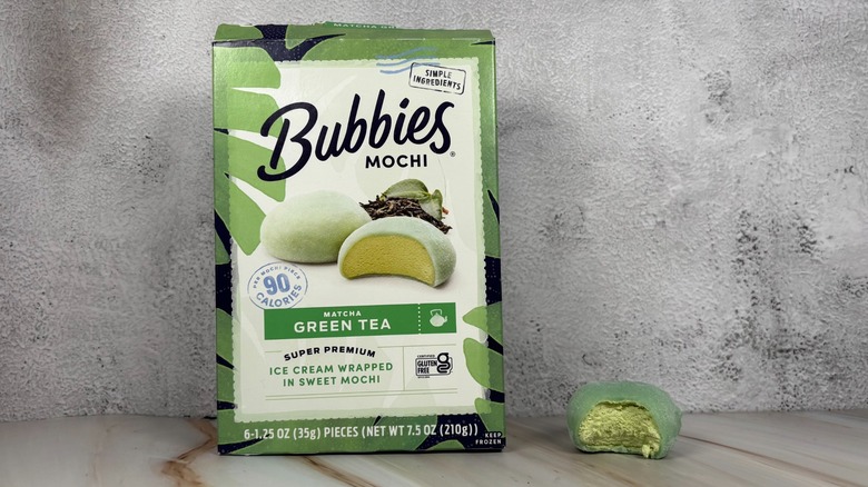 Matcha Green Tea mochi box next to mochi with bite taken out of it on table