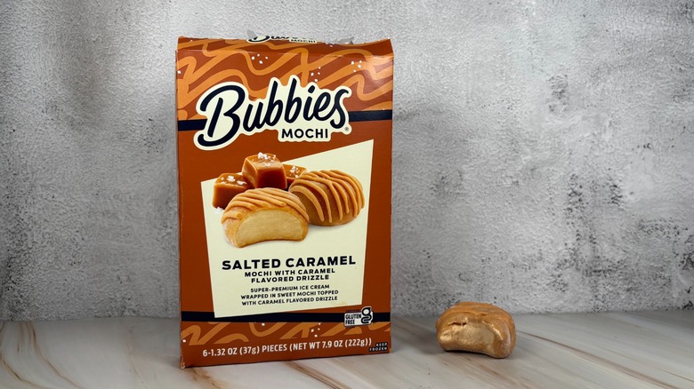 Bubbies Salted Caramel mochi box next to mochi with bite taken out of it on table