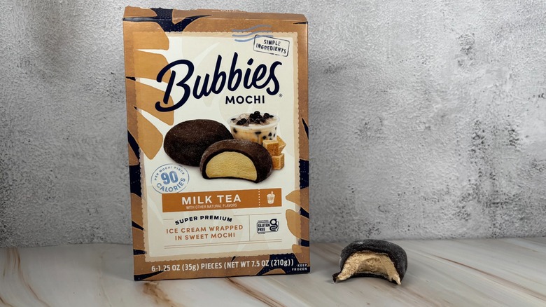 Bubbies Milk Tea mochi box next to mochi with bite taken out of it on table