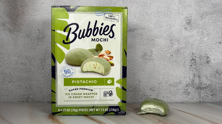 Bubbies Pistachio mochi box next to mochi with bite taken out of it on table