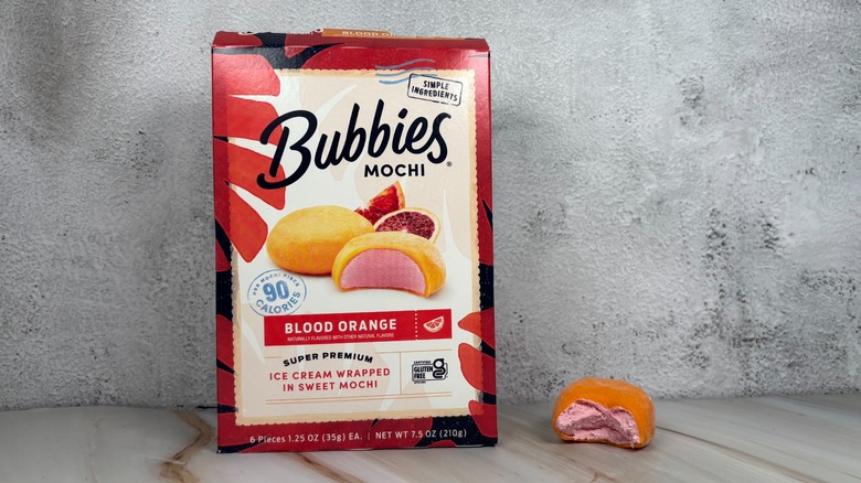 Bubbies Blood Orange mochi box next to mochi with bite taken out of it on table