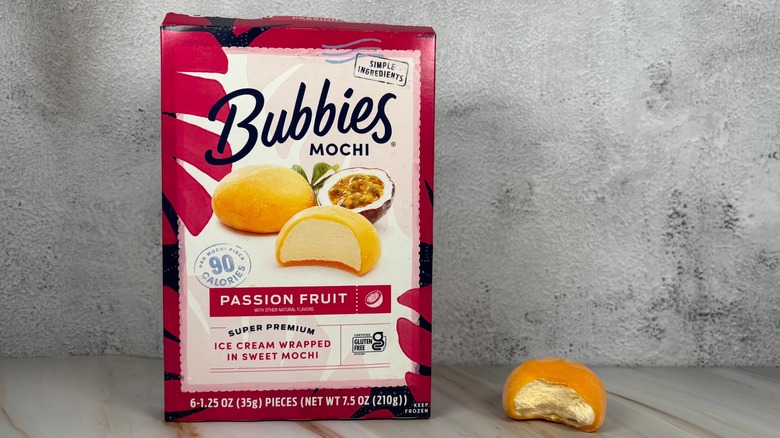 Bubbies Passion Fruit mochi box next to mochi with bite taken out of it on table