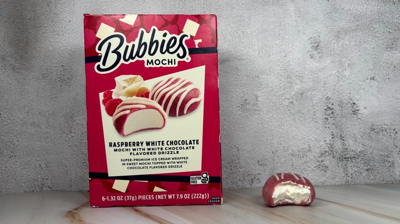 Bubbies Raspberry White Chocolate mochi box next to mochi with bite taken out of it on table