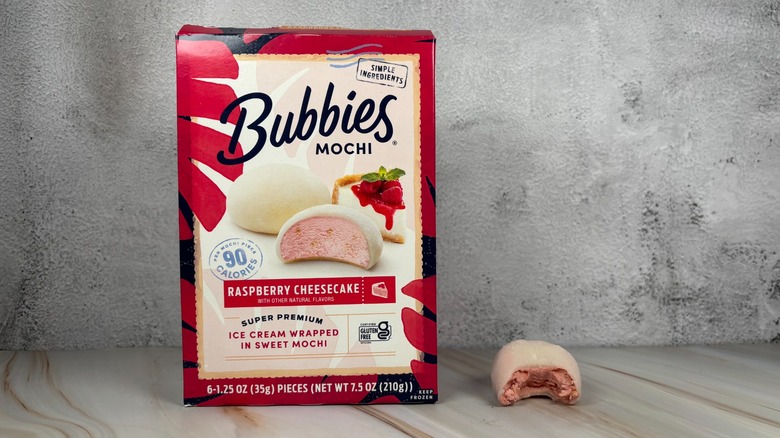 Bubbies Raspberry Cheesecake mochi box next to mochi with bite taken out of it on table