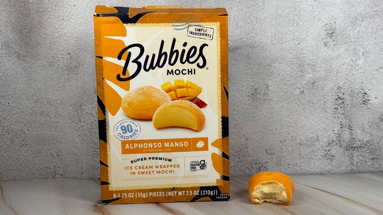 Bubbies Alphonso Mango mochi box next to mochi with bite taken out of it on table
