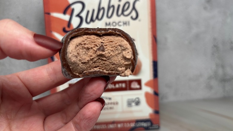 Hand holding Bubbies triple chocolate mochi with bite taken out of it