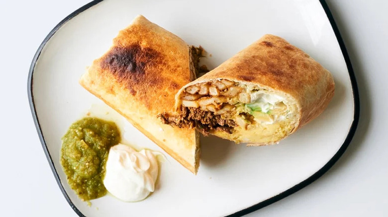 California Breakfast Burrito on white plate with salsa and sour cream